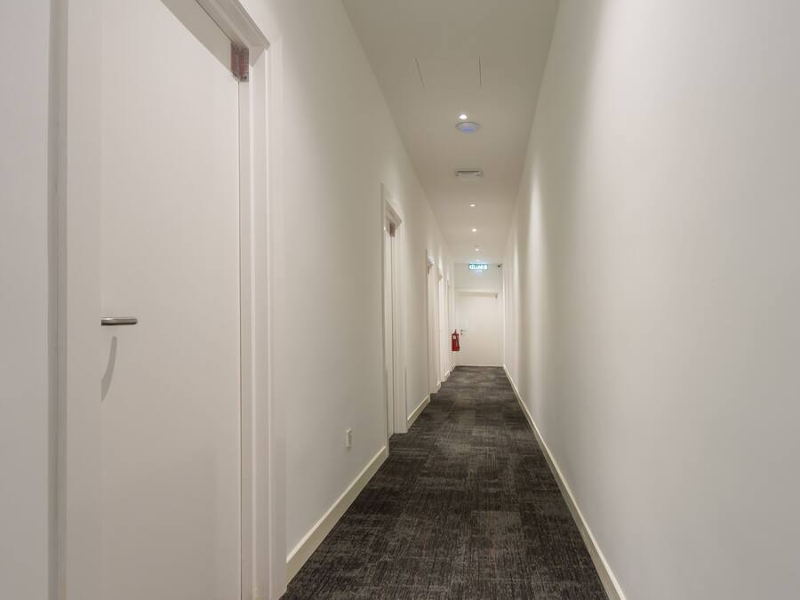 A long, narrow hallway with white walls and a carpeted floor.