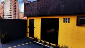 A building with a yellow facade, a black door, and a garage door. - Nomad - Norte Sul, Cambui (Campinas)