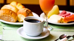 A breakfast setting with croissants, a glass of orange juice, and a cup of coffee on a table with a green tablecloth. - Nomad - Norte Sul, Cambui (Campinas)
