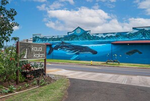 A mural of a whale and mountains on a building, with a sign that reads "Kauai Kailani".