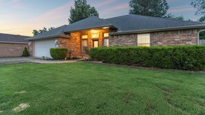 A residential house with a brick exterior, a garage, and a well-maintained lawn. - Your Home Away from Home  (Lowell)
