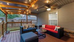 A covered patio with wicker furniture, a round table, and a ceiling fan. - Your Home Away from Home  (Lowell)