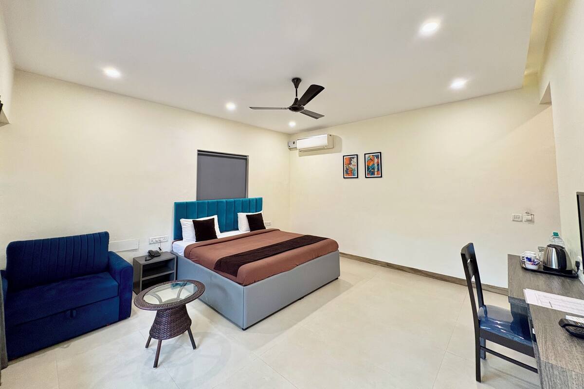A modern bedroom with a bed, a blue sofa, a small table, and a chair.