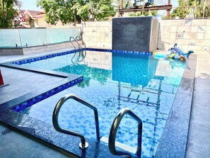 A swimming pool with clear blue tiles and metal handrails. - Girivihar Holiday club - Pure Veg (Mawal)