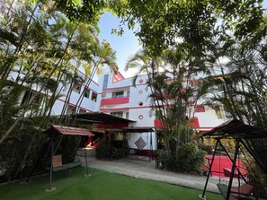 A building with multiple floors, surrounded by lush greenery and a well-maintained lawn. - Girivihar Holiday club - Pure Veg (Mawal)