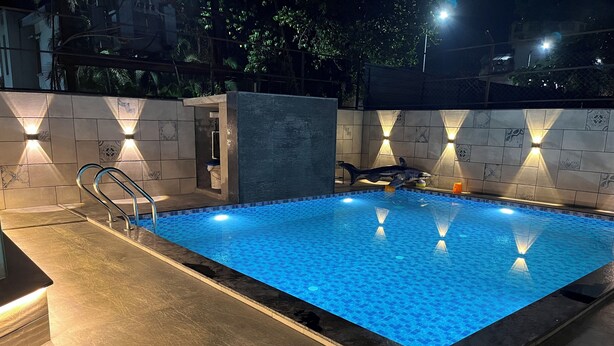 Ein rechteckiger Pool mit einer gefliesten Kante, umgeben von Wänden mit integrierten Leuchten.