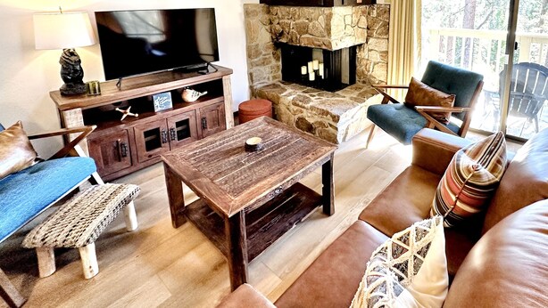 A cozy living room with a stone fireplace, a television, and comfortable seating.