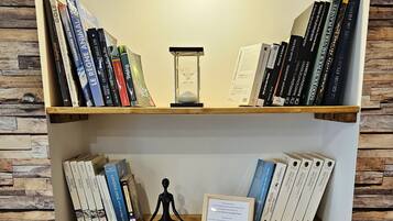 Une bibliothèque contenant divers ouvrages, un sablier et des objets décoratifs.