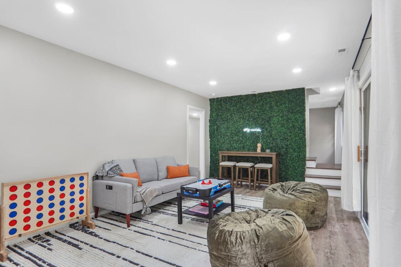 Ein modernes Wohnzimmer mit grauem Sofa, Couchtisch, grüner Wand und einer Holz-Spielgegend.