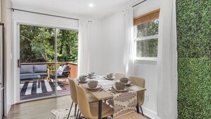 A dining area with a table set for four, a sofa, and a view of the outdoors. - Game Room, Balcony, Fire Pit, 5 Bed, 4 Bath, WFH (Charlotte)