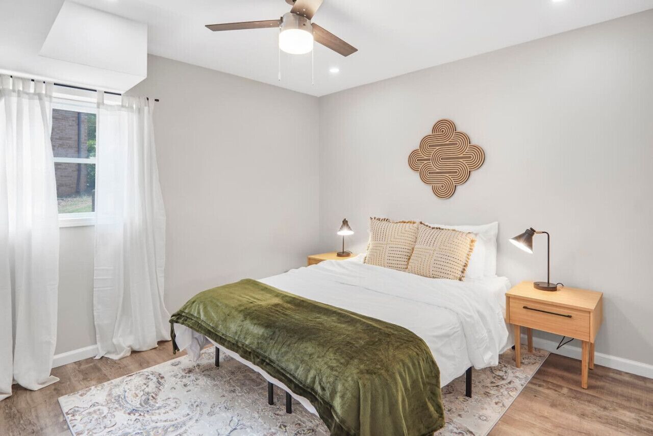 Ein Schlafzimmer mit Bett, Nachttischen, Deckenventilator und Wanddekoration.