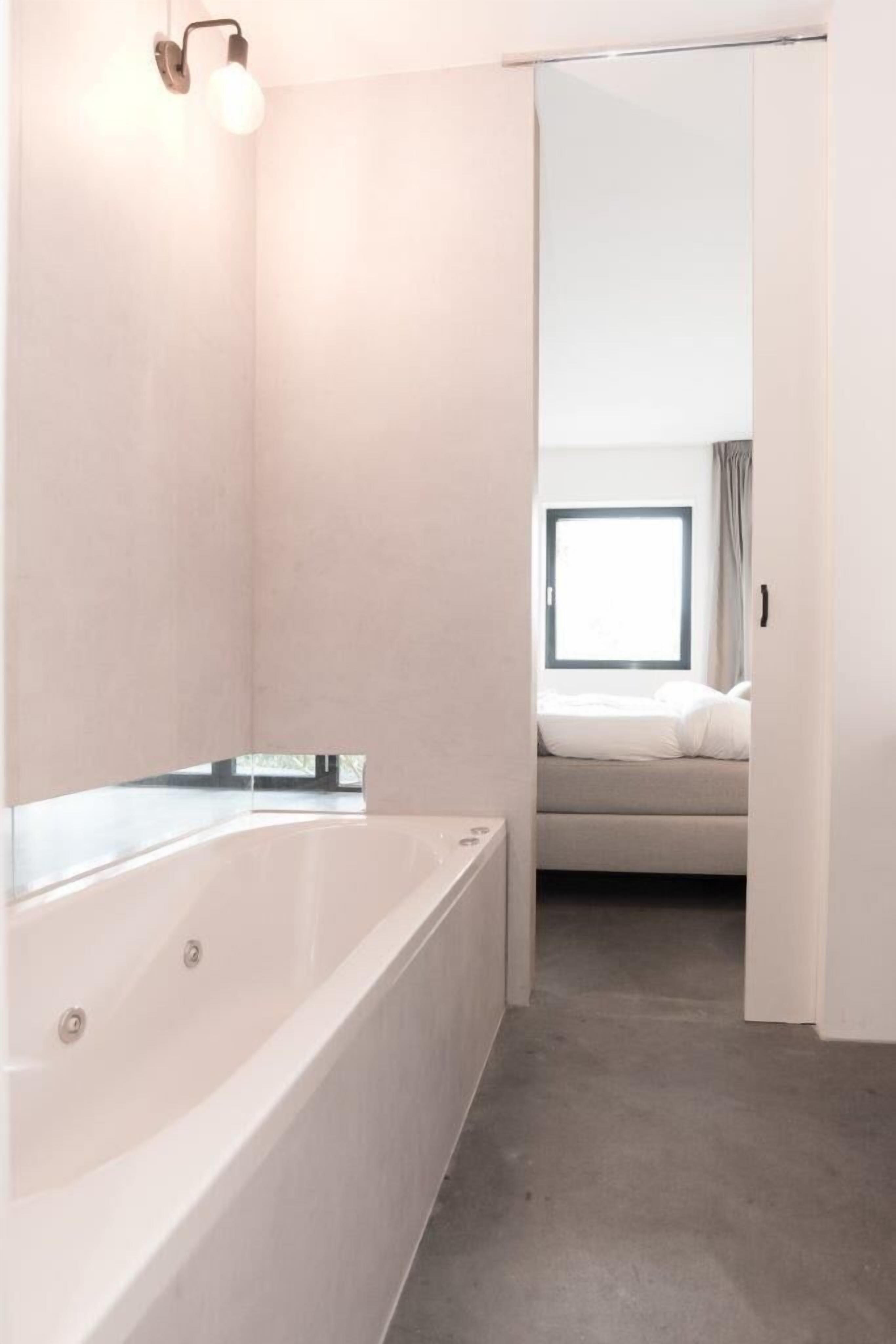 A modern bathroom with a large bathtub, a mirror, and a light fixture.
