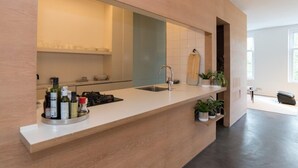 Une cuisine moderne dotée d’un grand îlot central, d’appareils électroménagers intégrés et de plantes en pot.