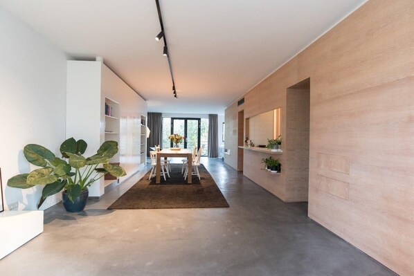 Un intérieur moderne comprenant un coin repas, une grande plante et un comptoir de cuisine.