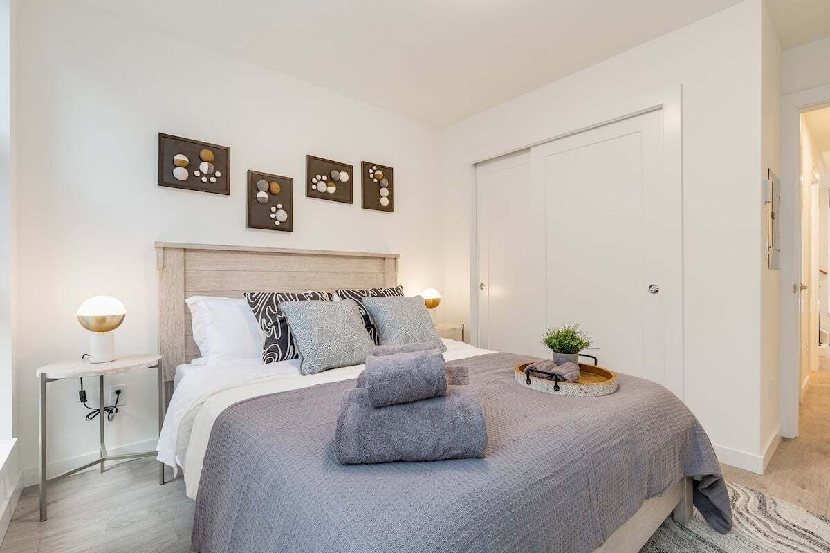 Ein modernes Schlafzimmer mit einem großen Bett, Nachttischen, einer Kopfteil und Wandbildern.