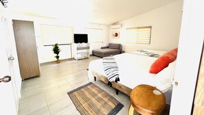 Ein Schlafzimmer mit einem Bett, einem Sofa, einem Fernseher und einem kleinen Tisch.