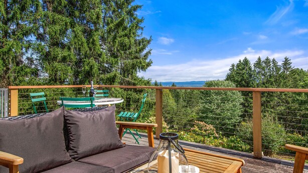 Een houten terras met een bank, een tafel en een lantaarn.