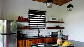 Una cocina moderna con armarios de madera, un refrigerador de acero inoxidable, un microondas y una encimera negra.