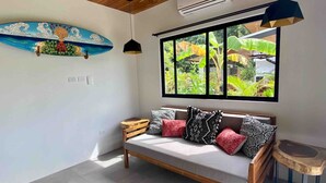 Una habitación moderna con un banco de madera, una decoración de tabla de surf colorida y un ventanal con vistas a zonas verdes.