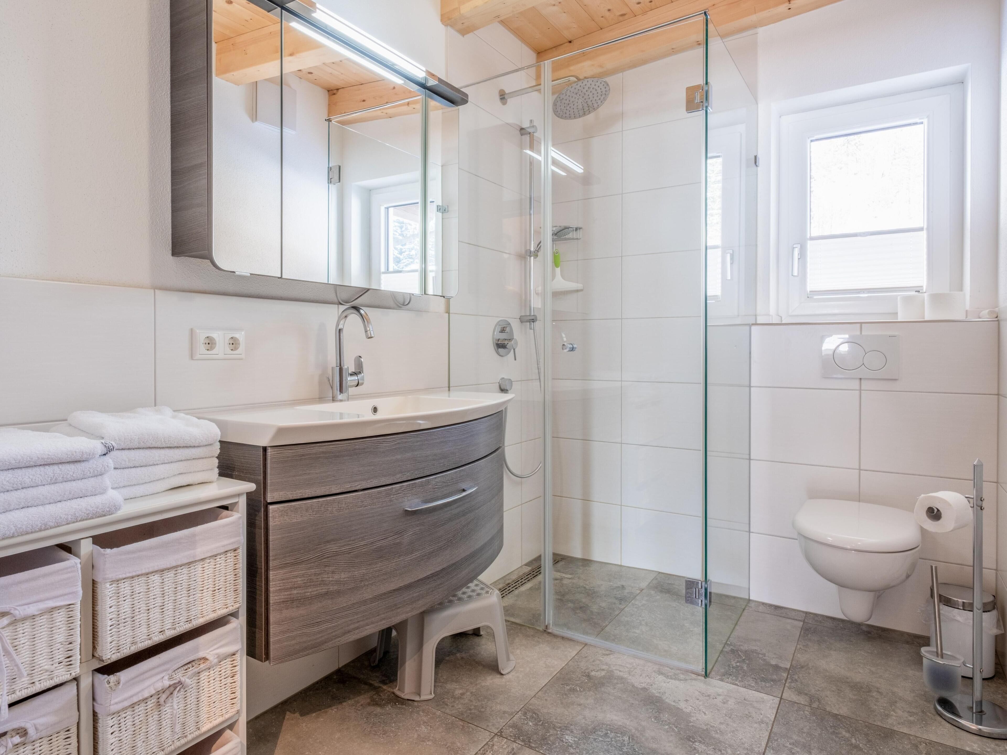 A modern bathroom with a glass-enclosed shower, a vanity with a mirror, and a toilet.