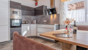 Een moderne keuken met inbouwapparatuur, een houten eettafel en hanglampen.