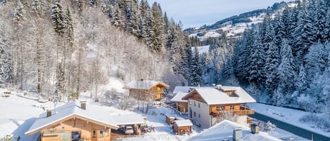 A snow-covered lodge with multiple cabins, a ski lift, and a forested backdrop.