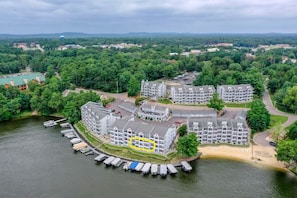 Ein Hotel am Wasserufer mit mehreren Gebäuden, vor Anker liegenden Booten und einer umliegenden bewaldeten Landschaft.