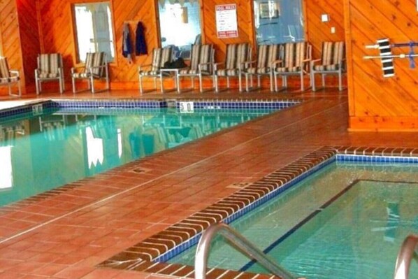 An indoor swimming pool with wooden walls and a tiled floor.