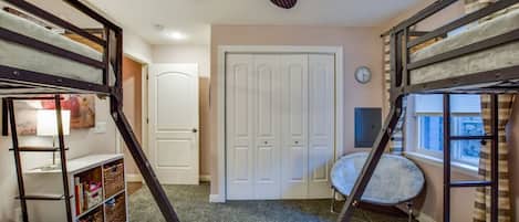 Una habitación con literas, ventilador de techo, una puerta y una ventana.