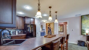 A kitchen with a central island, wooden cabinets, a refrigerator, and pendant lighting.