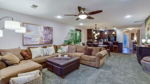 A spacious living room with a sectional sofa, a coffee table, and a ceiling fan.