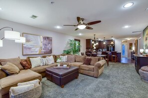 Ein geräumiges Wohnzimmer mit Ecksofa, Couchtisch und Essbereich, im Hintergrund eine Küche.