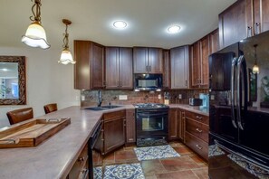 Una cocina moderna con armarios de madera oscura, un refrigerador negro y una isla grande con un lavamanos.