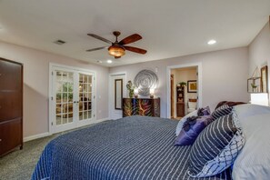 Ein Schlafzimmer mit einem großen Bett, einem Deckenventilator und einer Tür, die auf einen Balkon führt.