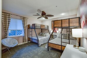 A room with bunk beds, a ceiling fan, a window with curtains, and a chair. - Kelly's Lakefront Escape - Huge Balcony (Wisconsin Dells)
