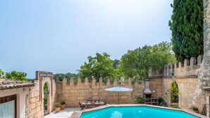 A swimming pool surrounded by stone walls and a stone chimney. - Sa Bisbal by Interhome (Moscari)