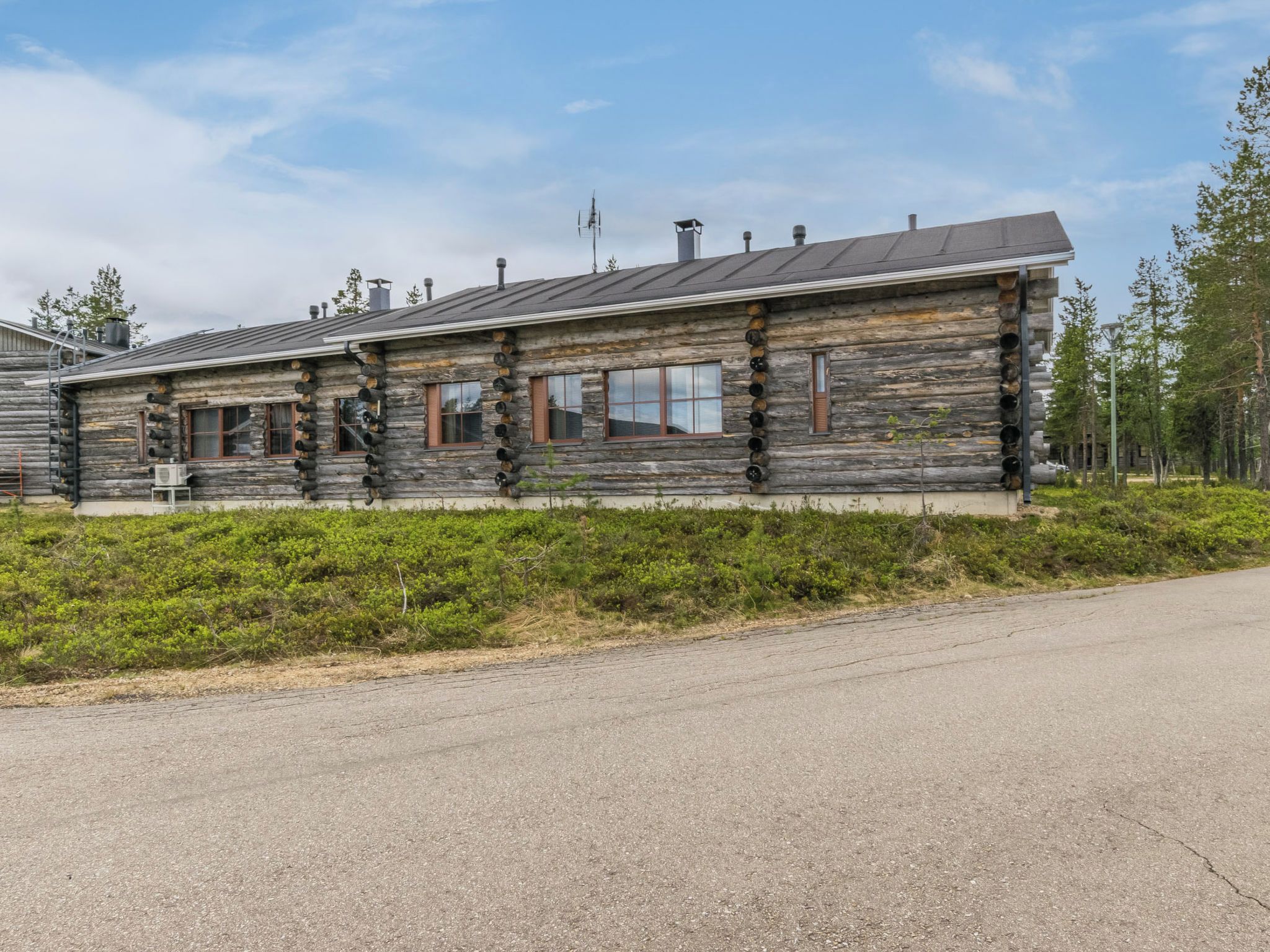 Une cabane en rondins avec un toit en métal, de nombreuses fenêtres et un petit porche.