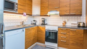 Een moderne keuken met houten kasten, een ingebouwde magnetron, een Bosch vaatwasser, een fornuis en een koffiezetapparaat.