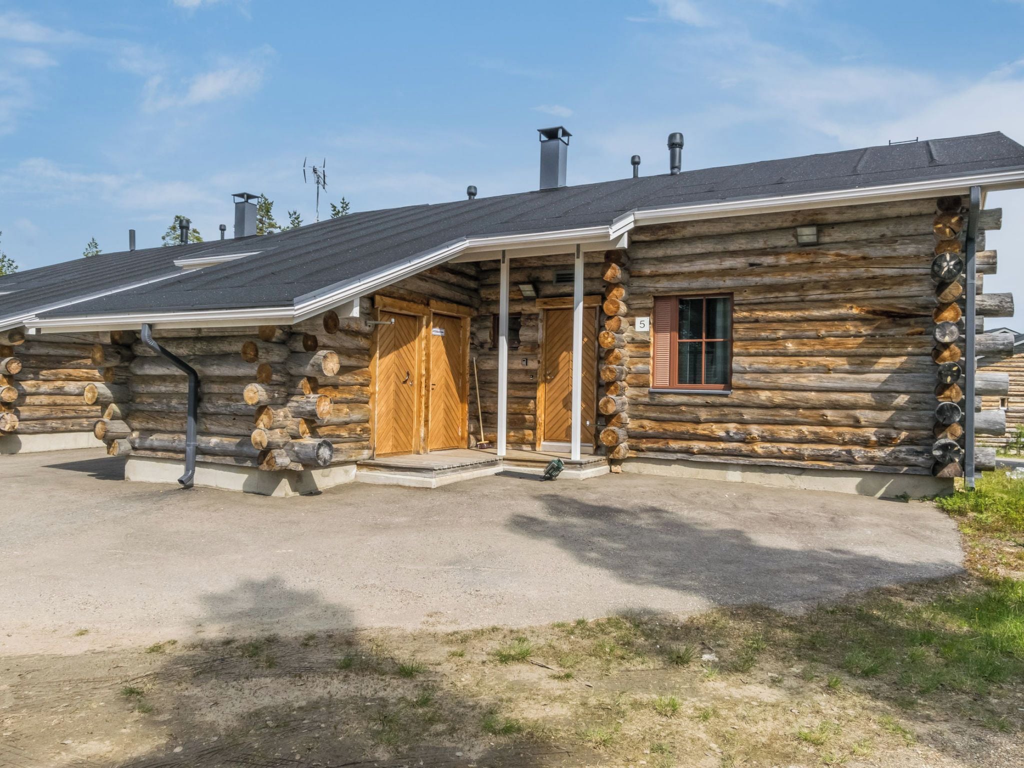 Une cabane en rondins avec un porche, une cheminée et une enseigne portant le chiffre « 5 ».