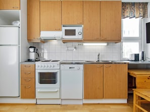 Una cocina funcional con armarios de madera, microondas integrado, estufa y lavavajillas.
