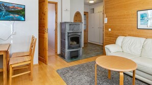 Ett mysigt vardagsrum med en öppen spis, en soffa, ett soffbord och en tv som är monterad på väggen.