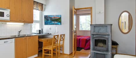 A compact kitchen with wooden cabinets, a microwave, and a dining area with a table and chairs.