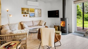 Una sala de estar acogedora con sofá, sillas, chimenea y obras de arte en la pared.
