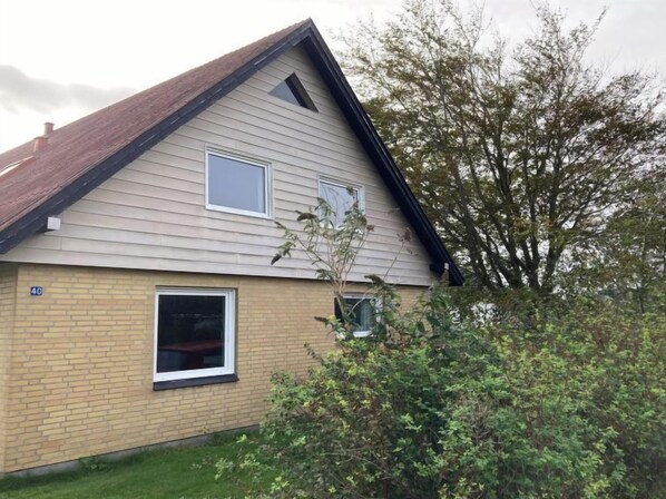 Stylish home with a gabled roof and brick exterior, featuring two windows and a small garden.