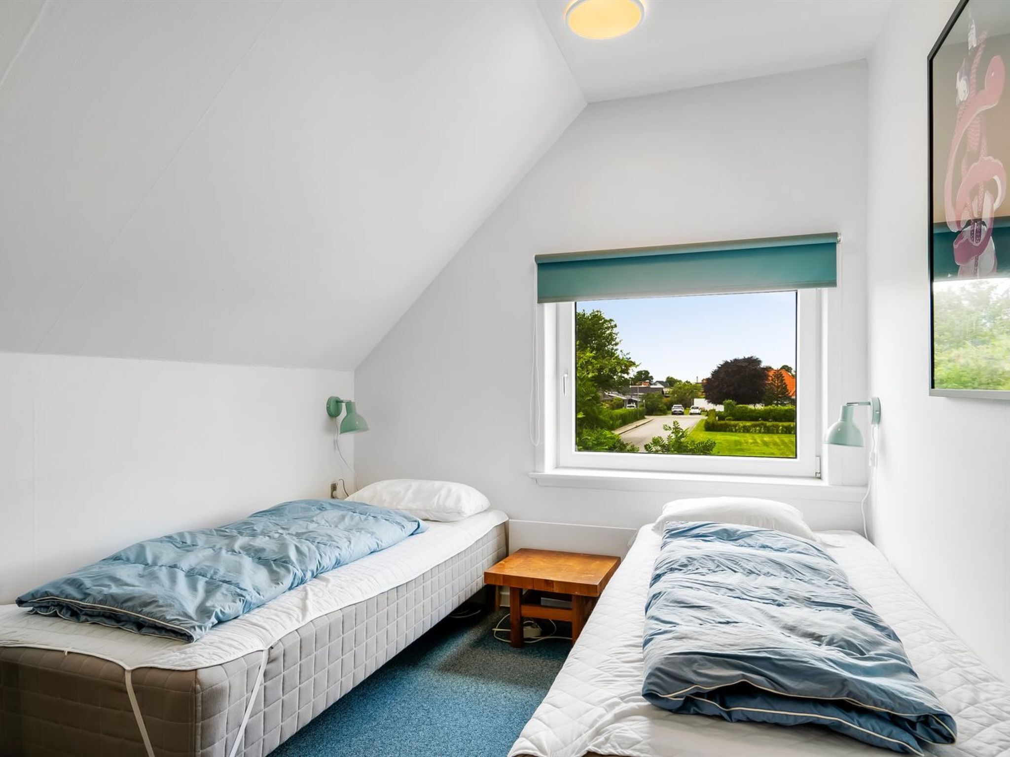 Une chambre de dortoir avec deux lits simples, une petite table et une fenêtre donnant sur un paysage verdoyant.
