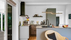 Una cocina moderna con microondas integrado, cafetera y una isla grande con pileta.