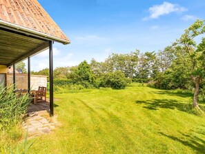Enjoy a serene outdoor space with a covered patio, lush greenery, and a well-maintained lawn.