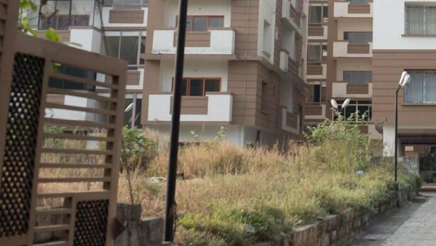 Um edifício residencial de vários andares com varandas, um poste de luz e uma entrada com portão.