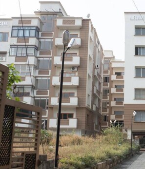 Un immeuble résidentiel à plusieurs étages, doté de balcons, d’un lampadaire et d’une entrée fermée par un portail.