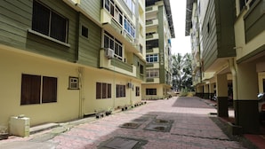 Um edifício residencial de vários andares com um caminho ladrilhado e plantas em vasos.